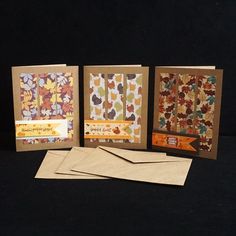 three cards with different designs on them sitting next to some envelopes and one is folded