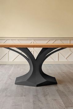 a wooden table sitting on top of a hard wood floor next to a white wall