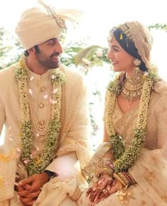 a man and woman dressed in wedding attire sitting next to each other on the ground