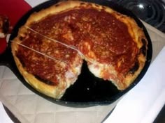 a deep dish pizza being cut in half on a stove top with a spatula