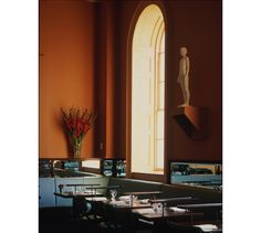 an empty restaurant with tables and chairs in front of a window that has a statue on the wall