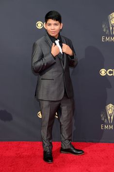 a young man in a suit and tie on the red carpet at an awards event