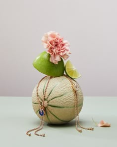 a green vase filled with flowers on top of a white table next to a pink flower