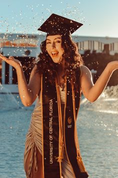 a woman wearing a graduation cap and gown throwing confetti in front of her