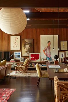 a living room filled with lots of furniture and wooden paneled walls next to windows