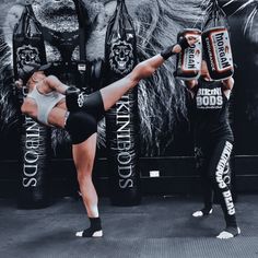 two women kickboxing in front of a lion wall with black and white posters