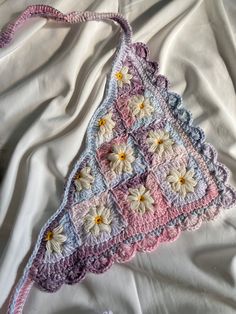 a crocheted purse sitting on top of a white sheet covered in fabric and flowers