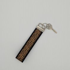 a keychain with a leopard print pattern on it and a black leather strap