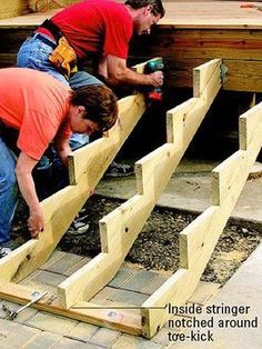 two men are working on some wooden steps outside with tools and construction materials around them