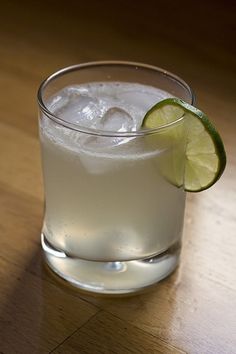 a close up of a drink on a table with a slice of lime in it