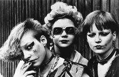 three women with makeup on their faces posing for the camera in front of a wooden fence