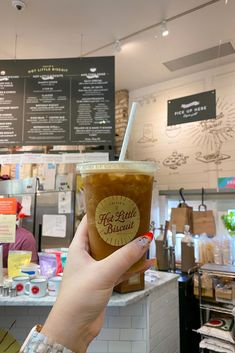 a woman holding up a cup of coffee in front of a counter with menus on it