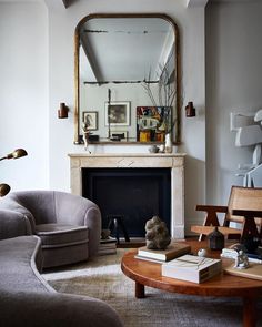 a living room filled with furniture and a fire place in front of a large mirror