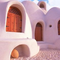 an adobe - style building with wooden doors and arched windows