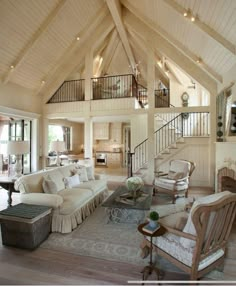 a living room filled with lots of furniture and a staircase leading up to the second floor