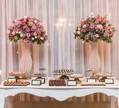 two vases filled with flowers sitting on top of a table covered in pastries