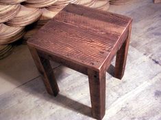 a small wooden table sitting in front of stacks of wood discs on the floor,