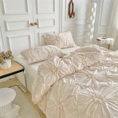 a large white bed sitting in a bedroom next to a table with flowers on it