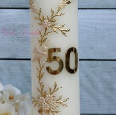 a close up of a candle with flowers on it and the number 50 written in gold