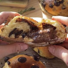 someone is holding up a pastry with chocolate chips on the outside and inside it's crust