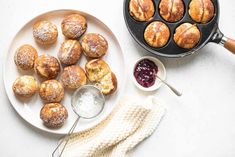 pastries and jams on a white plate next to a cast iron skillet