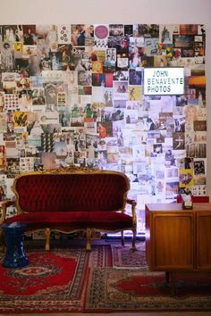 a red couch sitting in front of a wall covered with pictures