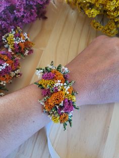 a person's arm with flowers on it sitting in front of a bowl full of flowers