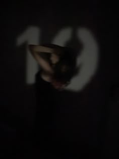 a person wearing a hat standing in the dark with their hands on their hipss