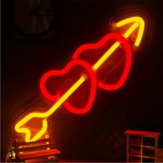 a red neon sign with an arrow pointing to the right on a black wall in a dark room