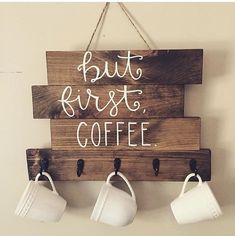 a wooden sign that says, but first coffee with three cups hanging from hooks on the wall