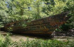 an old rusted boat sitting on top of a river