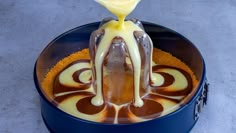 a spoon drizzling melted chocolate on top of an ice cream sundae