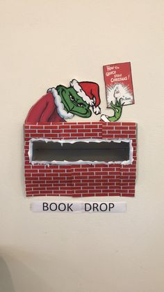 there is a sign on the wall that says book drop and an image of santa claus