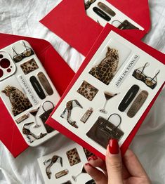 a woman's hand holding an open red box with leopard print items in it