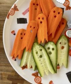 a white plate topped with cucumbers and carrots cut in to look like ghost faces