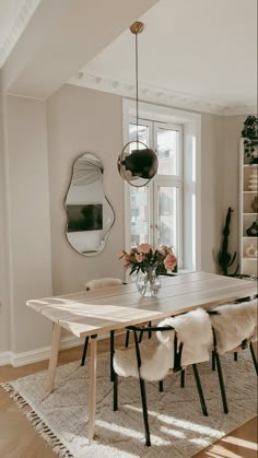 a dining room table with chairs and a vase filled with flowers on top of it