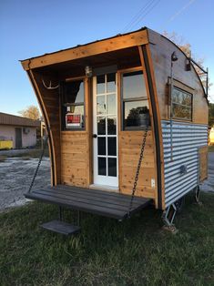 a tiny house on wheels with a swing in the front and door open to it