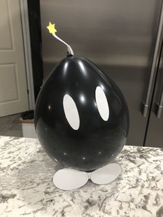 a large black balloon with two eyes and a star sticking out of it's side