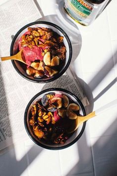 two bowls filled with food sitting on top of a table next to an open book