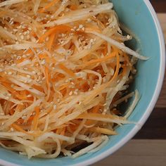 a blue bowl filled with shredded cheese on top of a wooden table