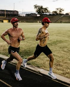 two shirtless men running on a track