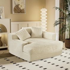 a white couch sitting on top of a rug in a living room next to a potted plant