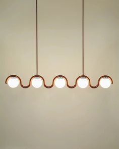 three lights hanging from the ceiling in a room with white walls and brown flooring