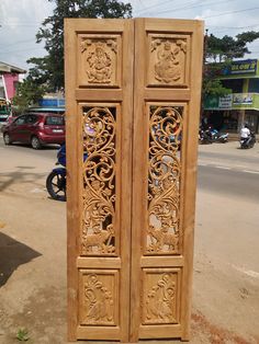 two carved wooden doors sitting on the side of a road