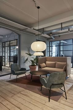 a living room filled with lots of furniture and large glass windows next to a wooden floor