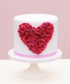 a white and pink cake with a heart made out of ruffles on top