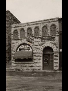 an old brick building with arched windows on the front and side doors, in black and white