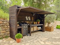 an outdoor bbq with potted plants and pots on the grill area next to it