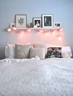 a bed with white pillows and pictures on the wall above it, in a bedroom