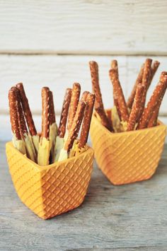 two yellow baskets filled with pretzels sitting on top of a wooden table next to each other